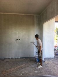 Rear view of man standing against wall at home