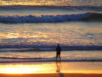 Silhouette man on beach against sky during sunset