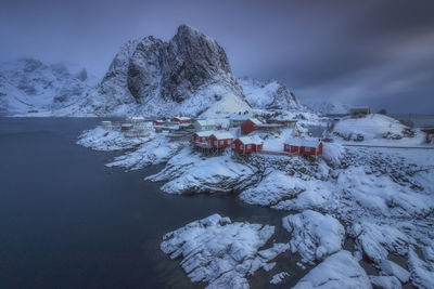 Scenic view of houses by lake at snowcapped mountains