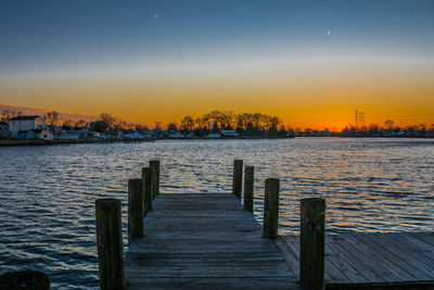 Pier over lake against sky during sunset