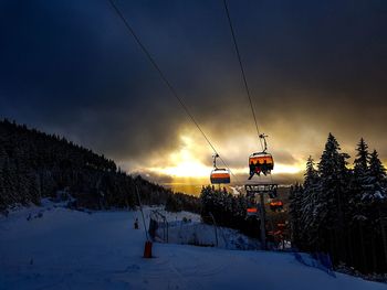 Ski lift over snowcapped mountains against sky during sunset