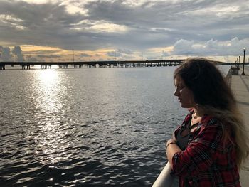 Side view of young woman standing by lake