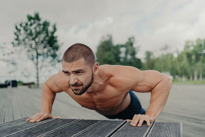 Shirtless young man exercising outdoors