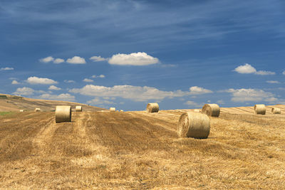 Hay bales on field against sky