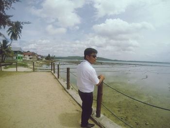 Rear view of man standing on beach against sky