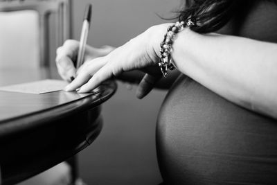 Mid section of pregnant woman writing on paper