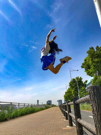 Low angle view of woman swinging against sky