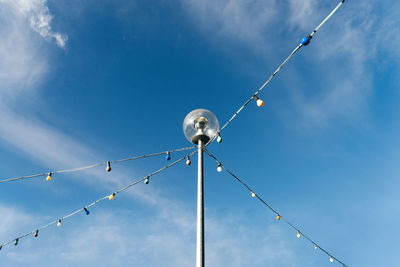 Low angle view of lamp posts and light bulbs against blue sky