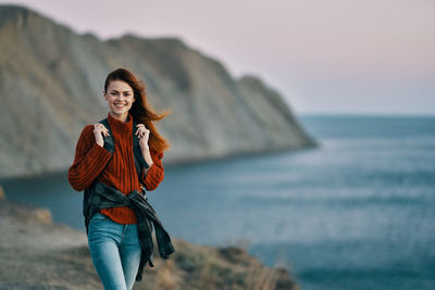 Portrait of young woman at beach against sky