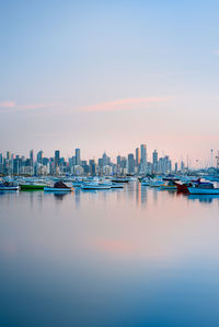 Sea and buildings in city at sunset