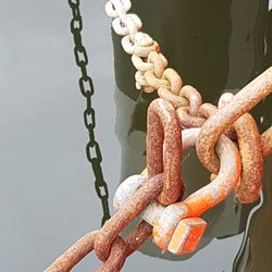 Close-up of rusty metal chain over river