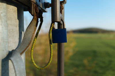 Close-up of padlock hanging on pole against sky