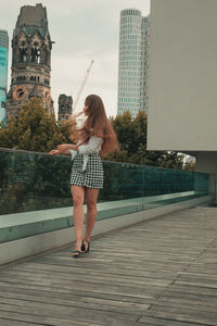 Young woman standing against buildings in city