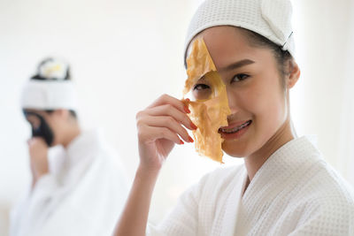 Young woman removing facial mask from face in spa