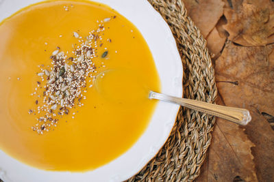 Top view of pumpkin soup cream with an autumn background of leaves and wood