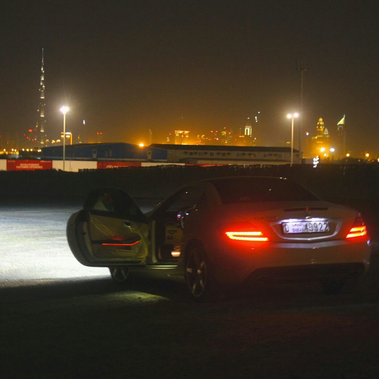 night, illuminated, transportation, street light, mode of transport, land vehicle, car, street, road, sky, city, lighting equipment, on the move, copy space, outdoors, building exterior, clear sky, dark, built structure, city life