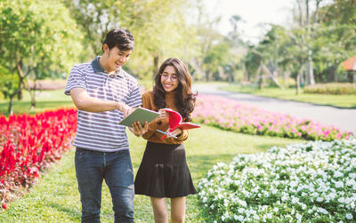 Cheerful friends looking at book in public park