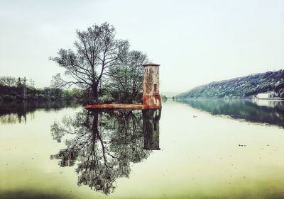 Reflection of tree in lake against clear sky