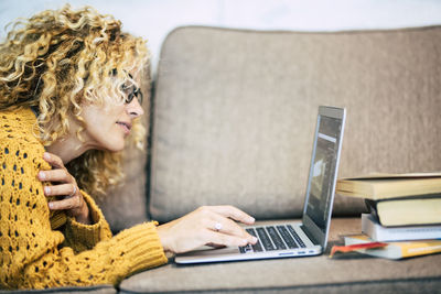 Woman using laptop while sitting on sofa at home