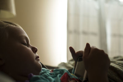 Girl holding toy while lying on bed at home