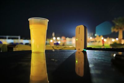 Close-up of drink on table against sky at night