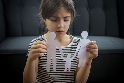 Sad girl with paper craft sitting at home