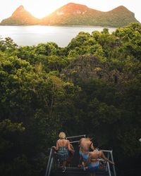 People by trees against lake and mountains