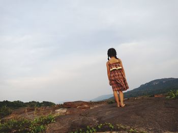 Rear view of woman standing on mountain road