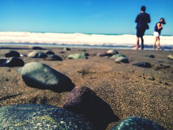 Close-up of pebbles on beach against sky