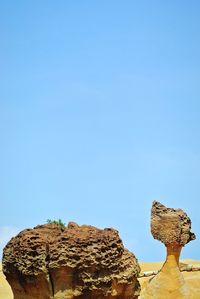 Low angle view of rocks against clear blue sky