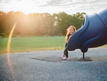 Cute girl sitting on slide at park