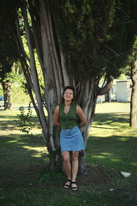 Portrait of a smiling young woman standing against trees