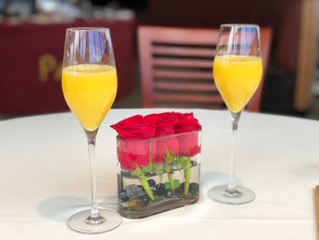 Close-up of drink in glasses by flowers on table