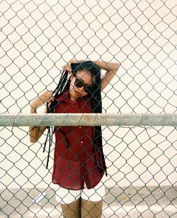Portrait of woman standing by chainlink fence