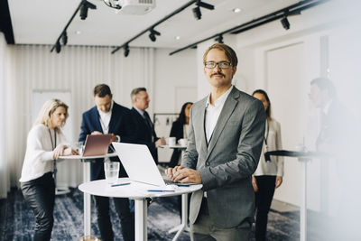 Portrait of businessman working over laptop while standing in office seminar