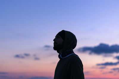 Thoughtful man standing against sky during sunset