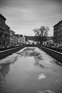 Canal by buildings against sky in city