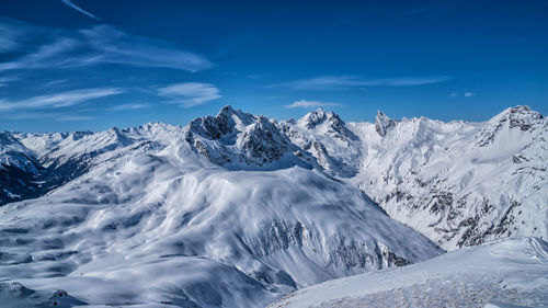 Scenic view of snowcapped mountains against blue sky