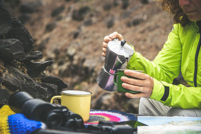 Woman pouring coffee in cup at forest