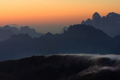 Scenic view of silhouette mountains against orange sky