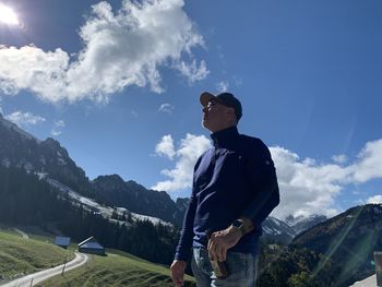 Man wearing sunglasses standing by mountain against sky