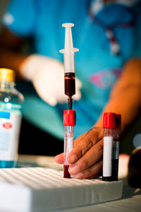 Midsection of doctor examining blood sample in test tube