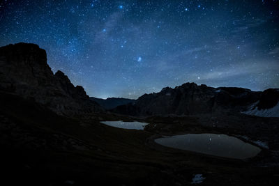 Scenic view of lake and mountains against sky at night
