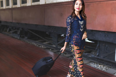 Beautiful asian malay woman travelling with carrying baggage at the train station.