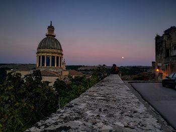 Temple by building against sky at dusk