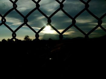 Chainlink fence against sky at sunset