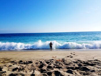 Man standing on beach against clear sky