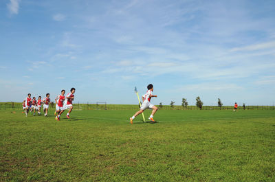 People playing on field against sky