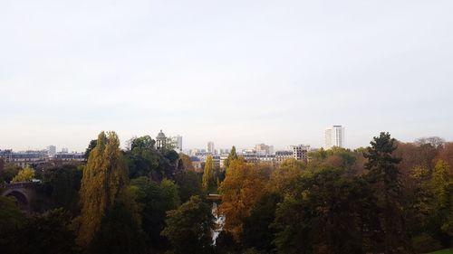 Trees and cityscape against sky