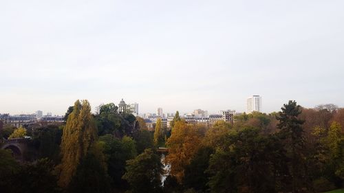 Trees and cityscape against sky